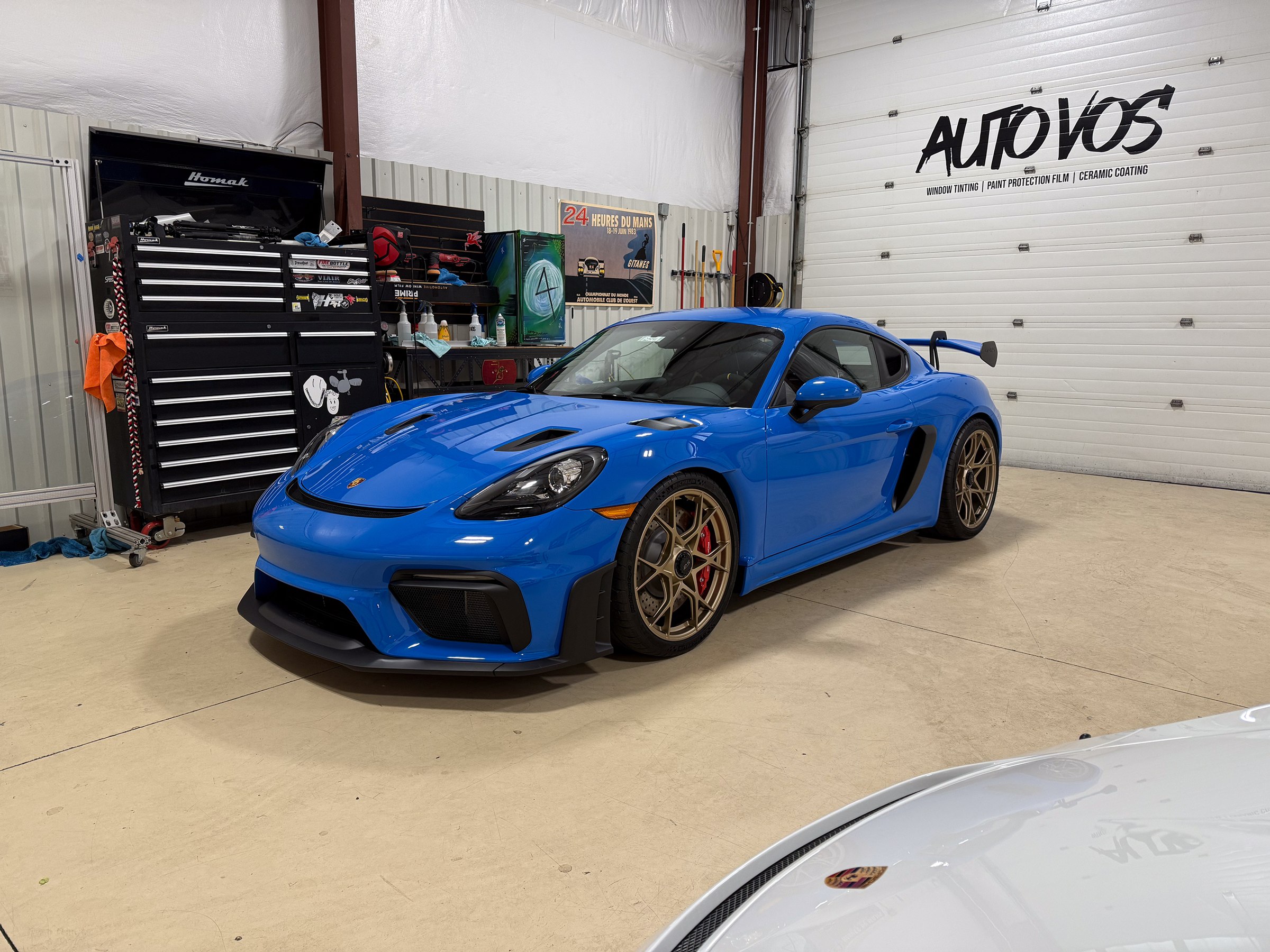 Blue Porsche Cayman with bronze wheels in the Auto Vos workshop Blue Porsche Cayman with bronze wheels in the Auto Vos workshop