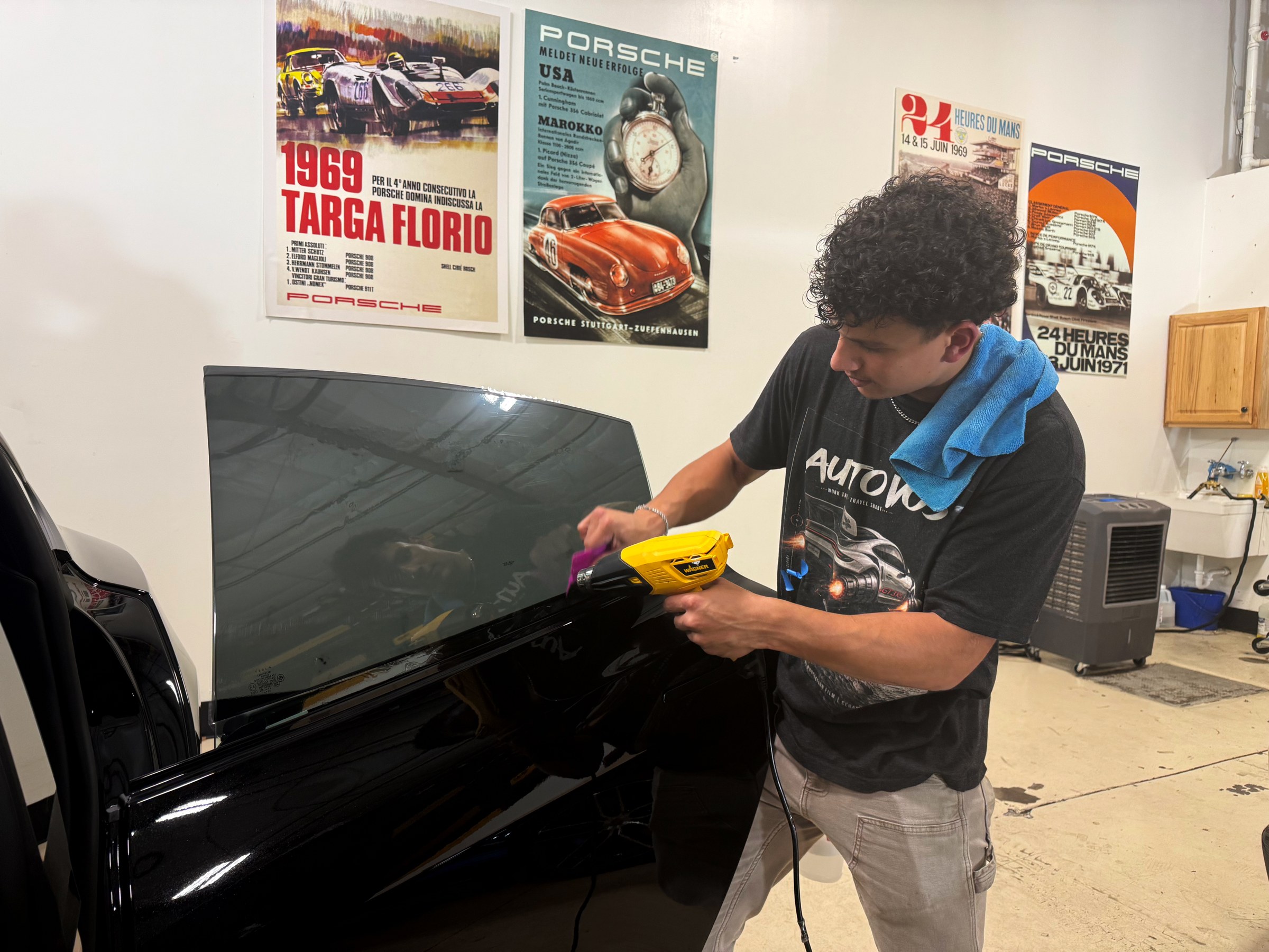 Installer working window tint across a car’s side glass Installer working window tint across a car’s side glass
